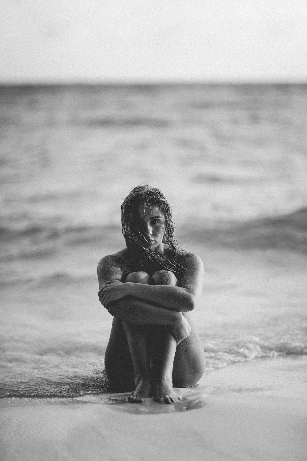 Foto in scala di grigi di donna in riva al mare
