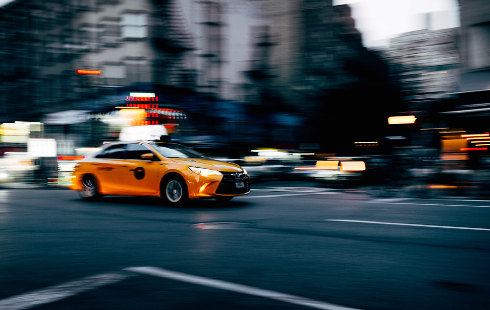 orange coupe running on gray street during daytiem
