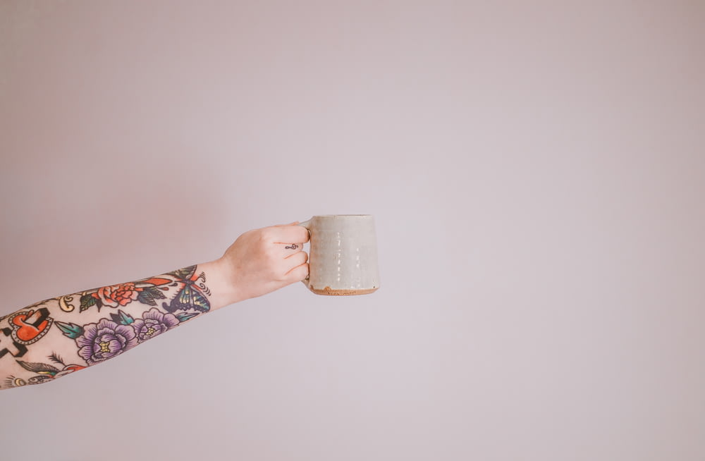 a person holding a coffee mug in their hand