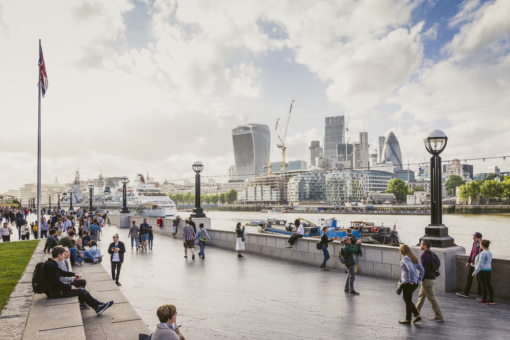 Turistas passeando na margem do Tâmisa com a cidade de Londres visível na outra margem