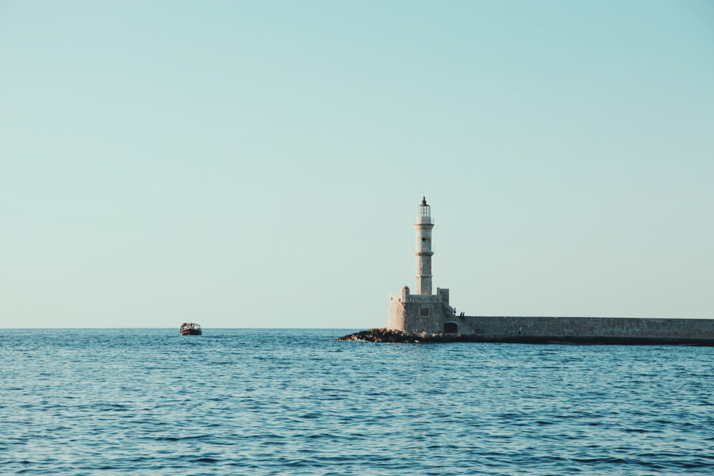 white and gray lighthouse surrounded by body of water under blue sky at daytime