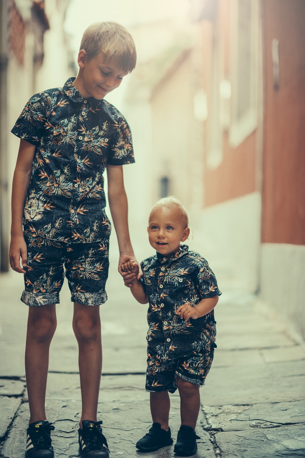 matching pair of boy's black and gray floral collared shirt and shorts standing on gray concrete area