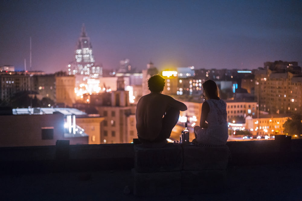 hombre y mujer relajándose en la azotea frente a edificios de gran altura