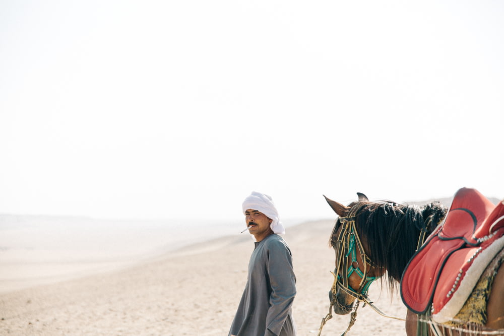 Mann zu Fuß mit Pferd in der Wüste