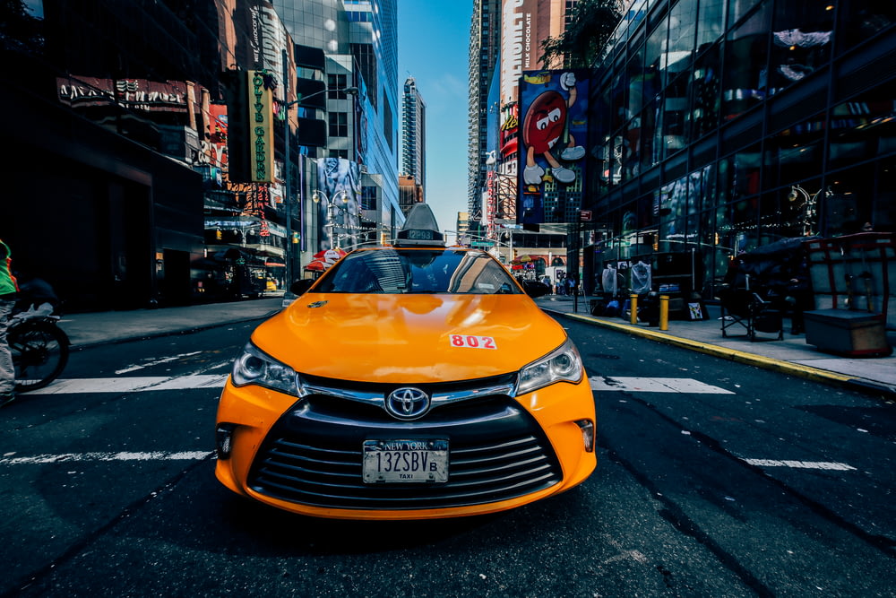Coche Toyota naranja en la carretera entre edificios