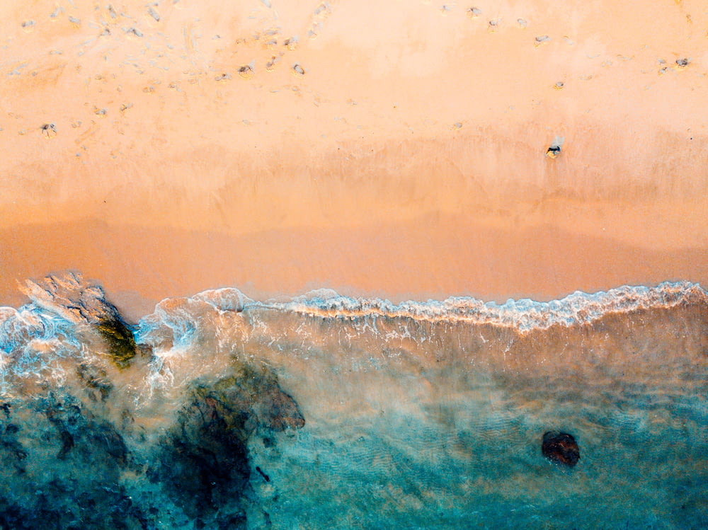 Toma de dron de playa y cuerpo de agua en arena marrón