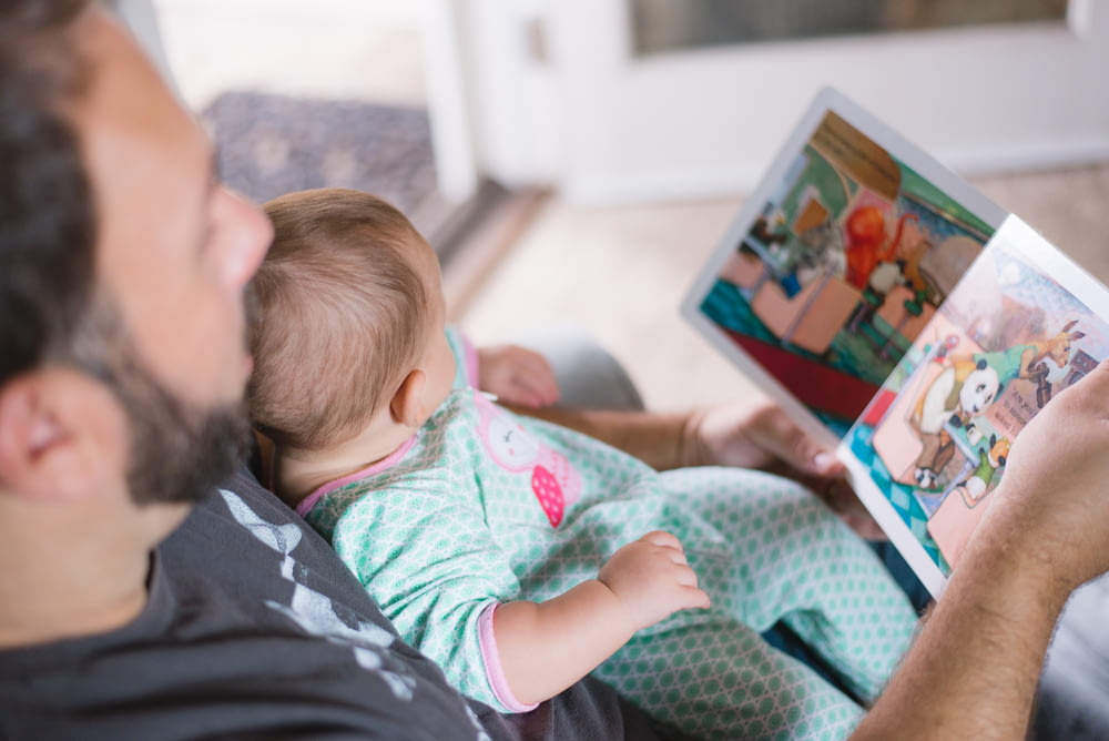 Person, die Baby trägt, während sie ein Buch liest