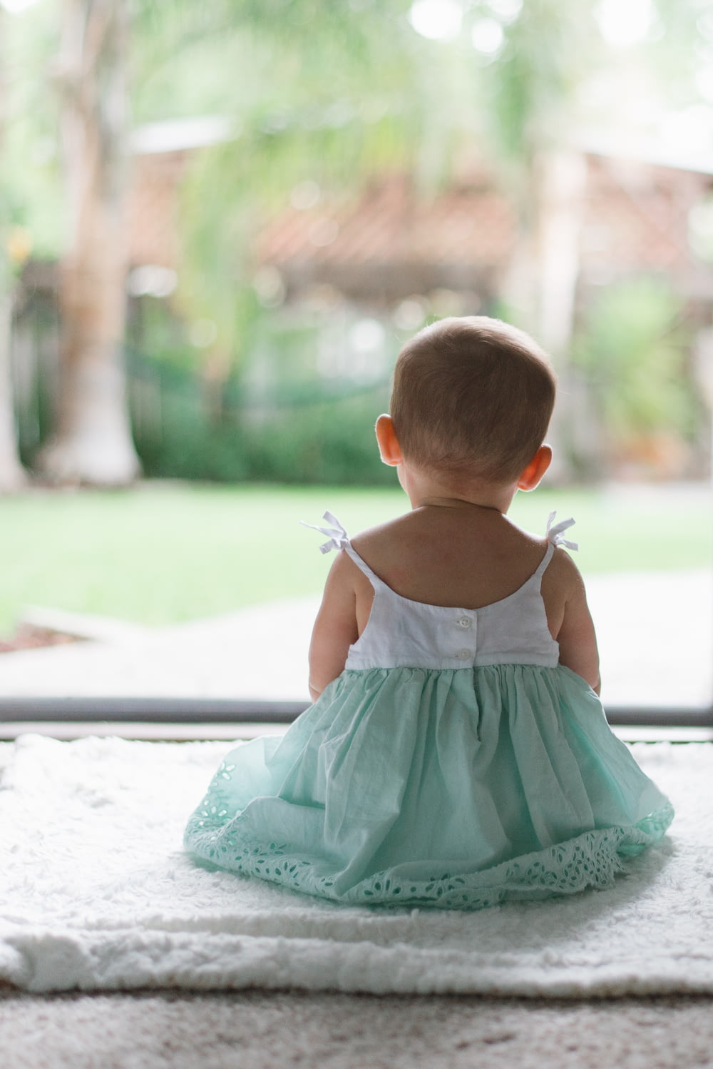 selective focus photo of toddler wearing sleeveless dress sitting on floor
