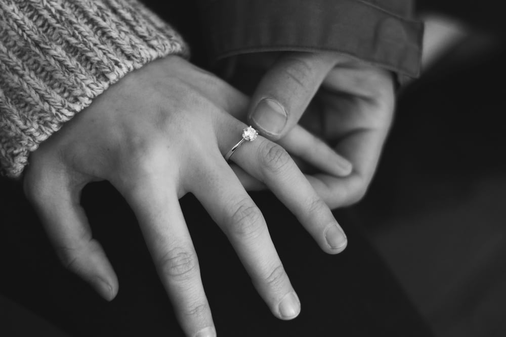 結婚指輪をはめ、手をつないでいる女性