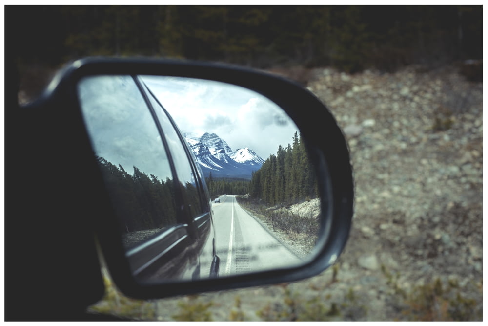 Fotografia Tilt Shift do espelho lateral refletindo a montanha coberta de neve