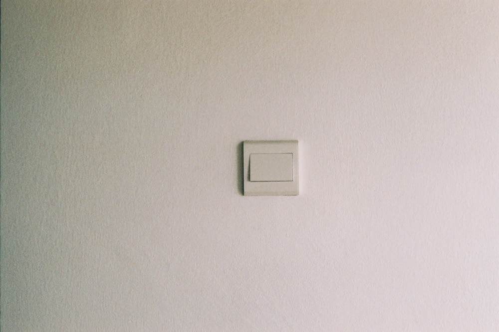 Interrupteur de lumière blanche sur mur peint en blanc