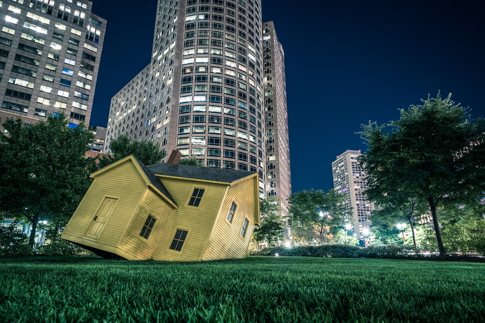 yellow house on green grass overlooking buildings at nighttime
