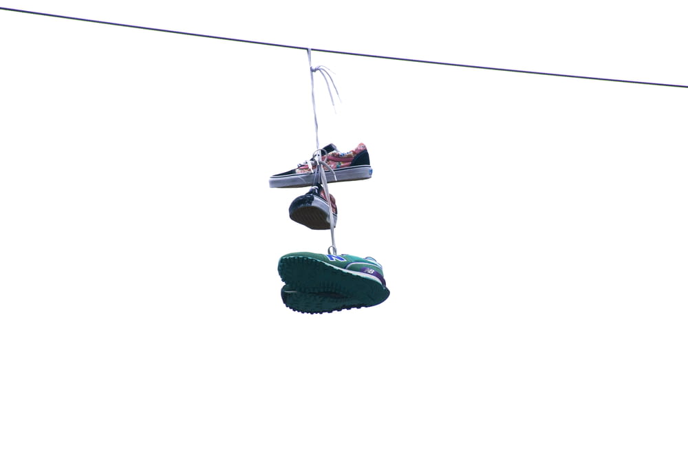 two pairs of shoes hanging on thread