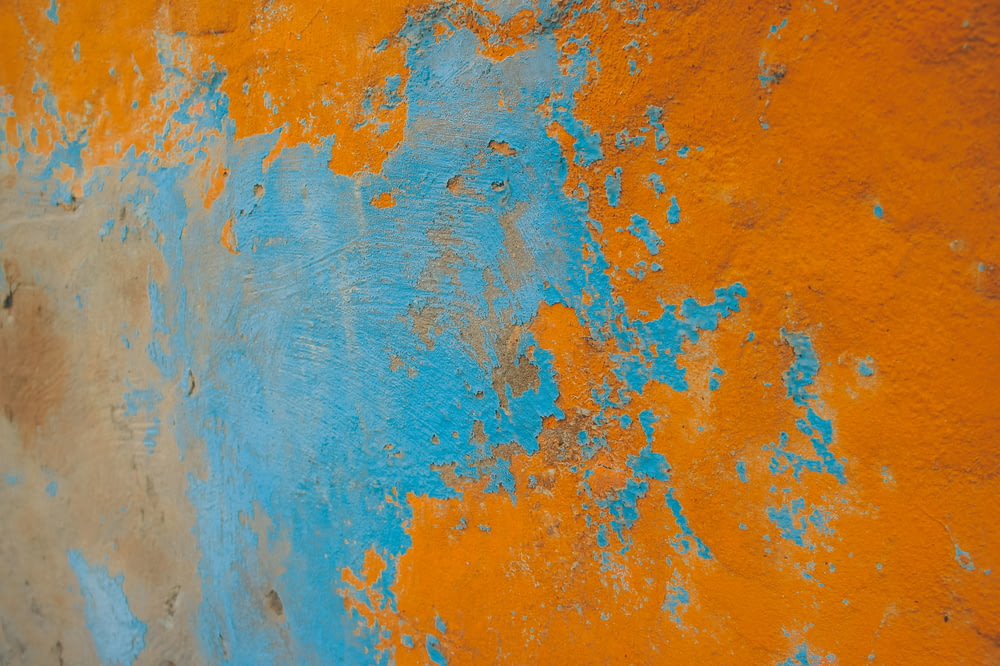 an orange and blue wall with peeling paint