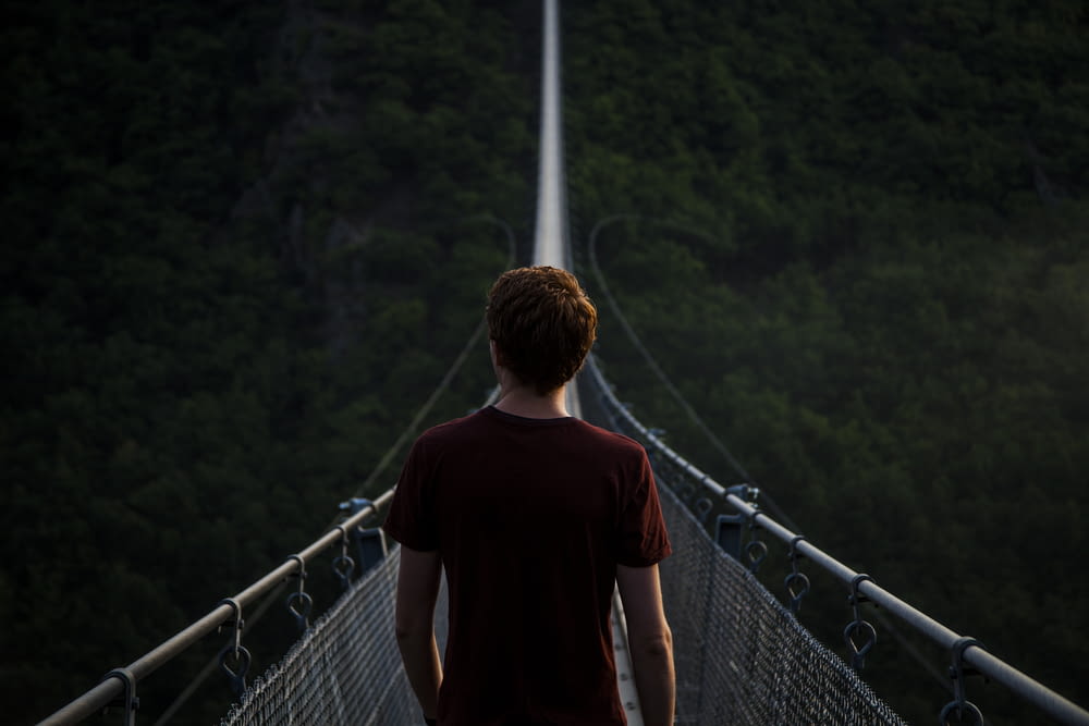 man standing alone on hanging bridge