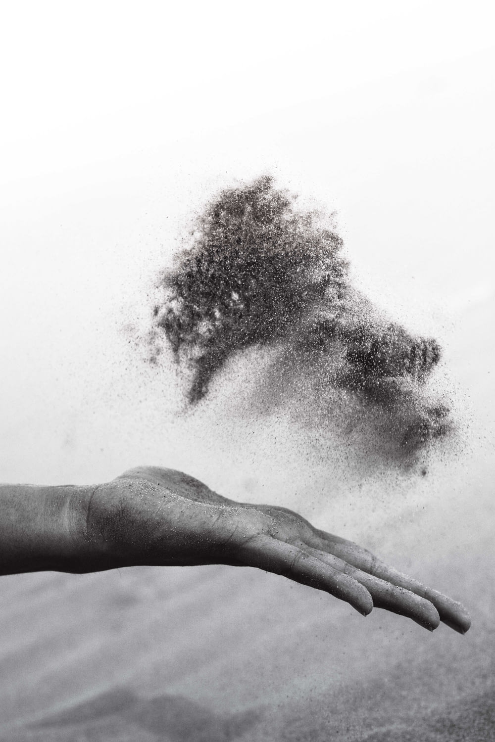 砂を広げる人の手のグレースケール写真