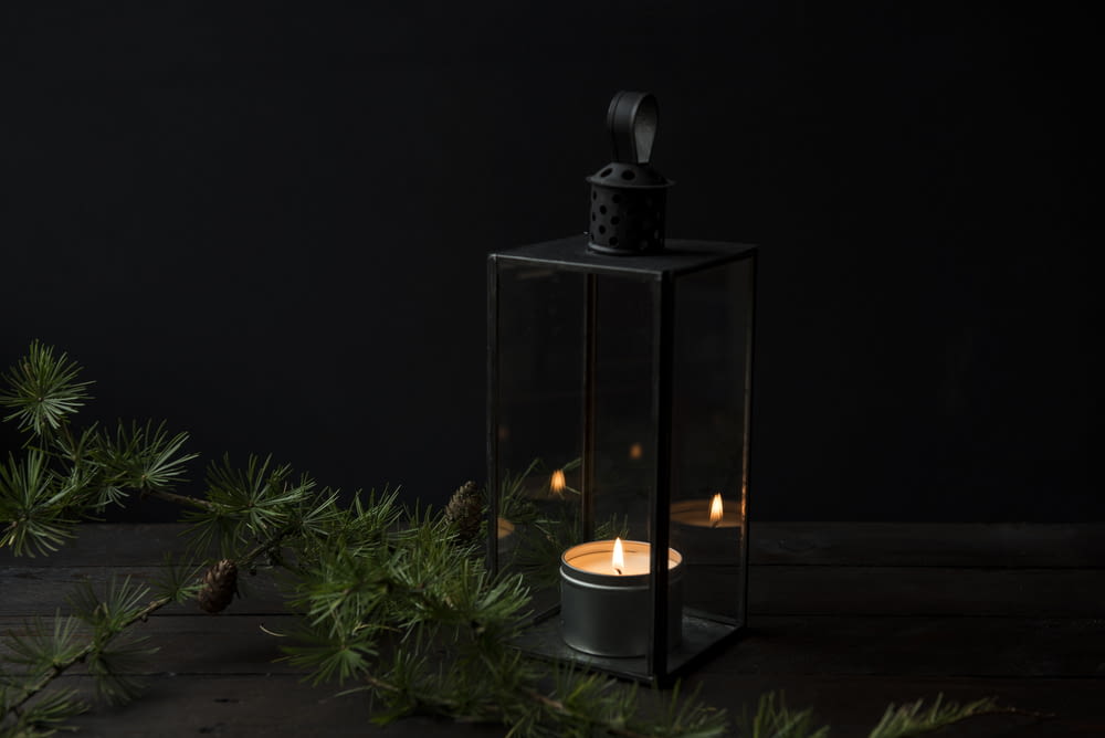 lighted candle inside black lantern holder