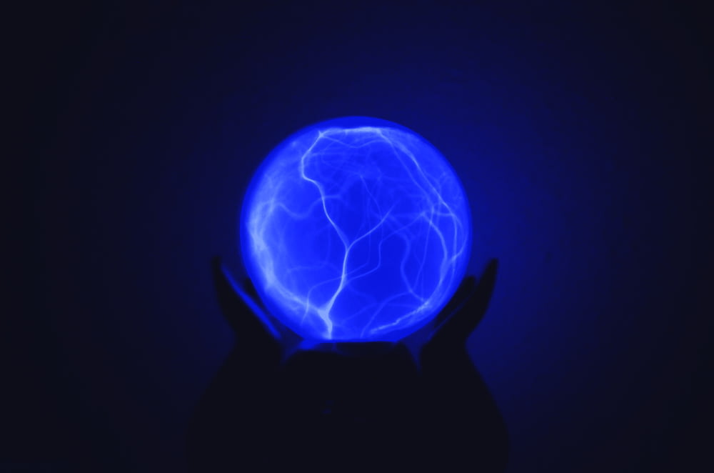 Photo en basse lumière d’une personne tenant une boule lumineuse bleue