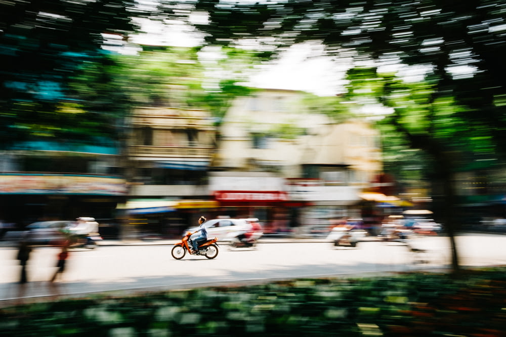 tilt shift photography of man riding motorcycle