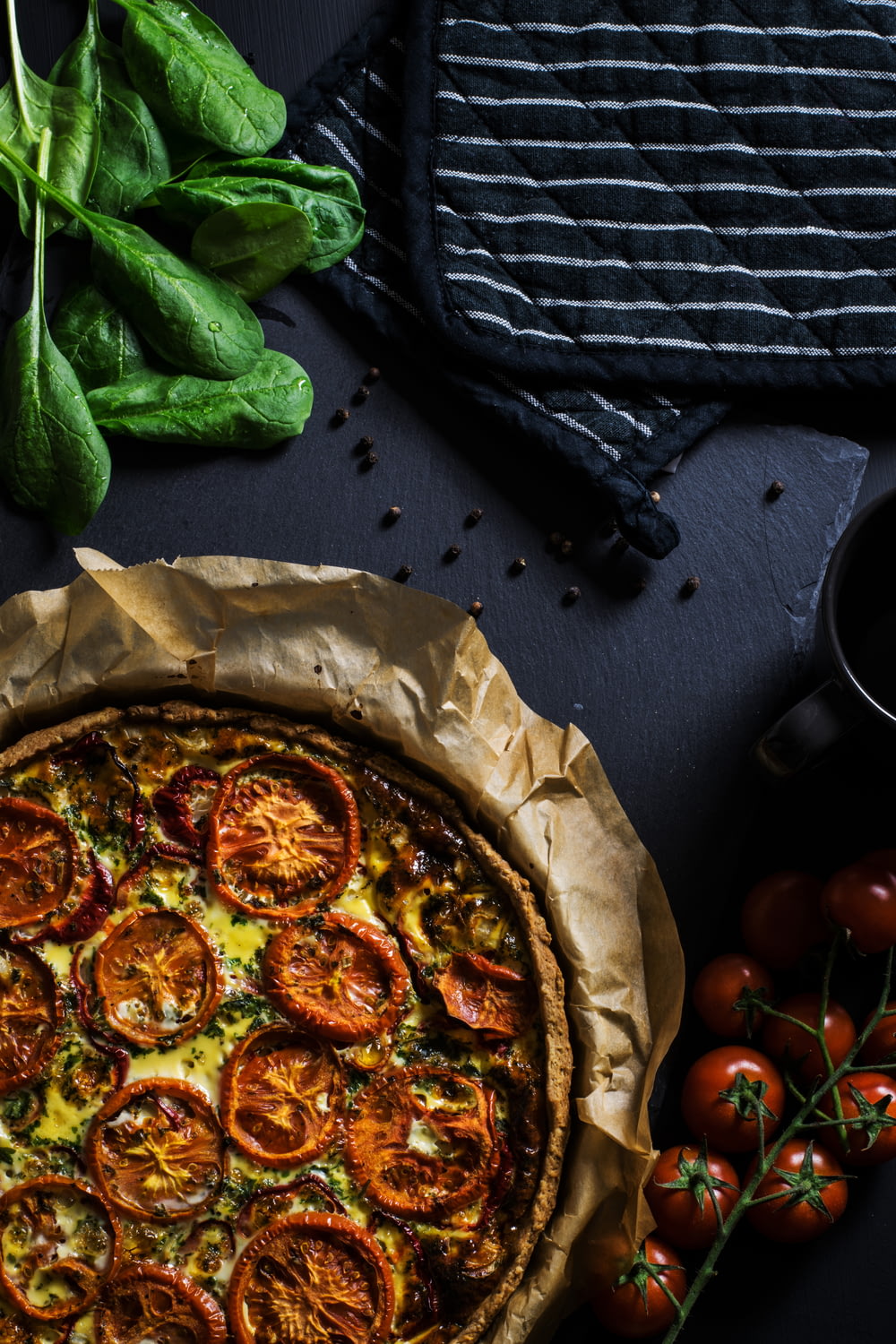 トマトとピザの横の2つの黒い鍋つかみのフラットレイ写真