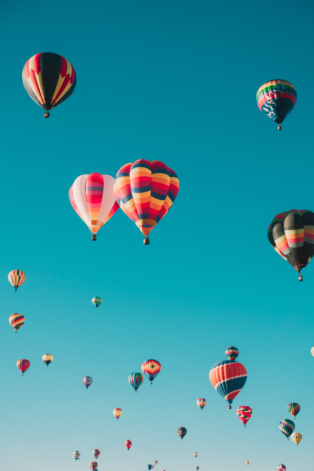 Balões de ar quente variados voando em alta altitude durante o dia