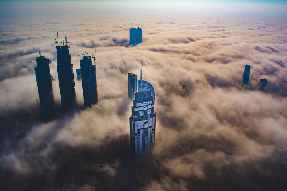 aerial photo of buildings surrounded by clouds during daytime