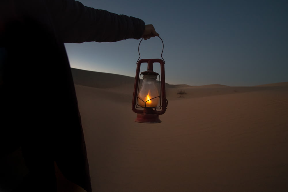 pessoa segurando lanterna de querosene vermelho