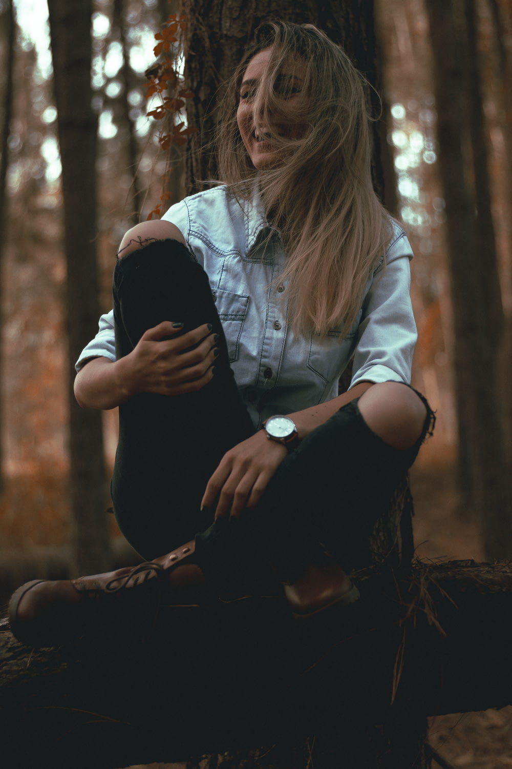 laughing woman leaning on gray tree trunk