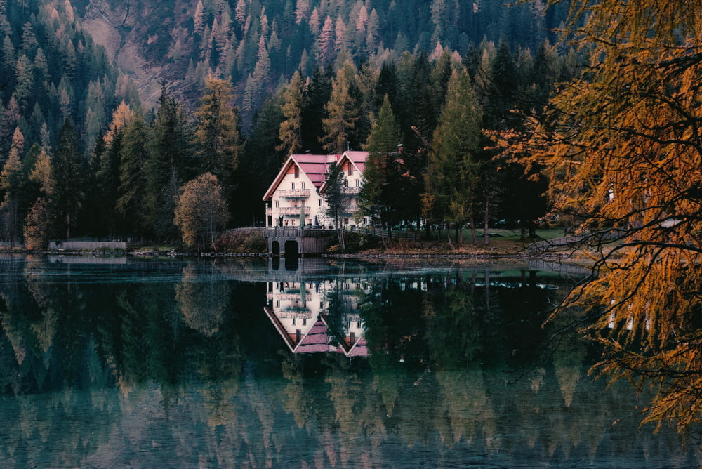 Foto da paisagem da casa branca e vermelha perto do lago
