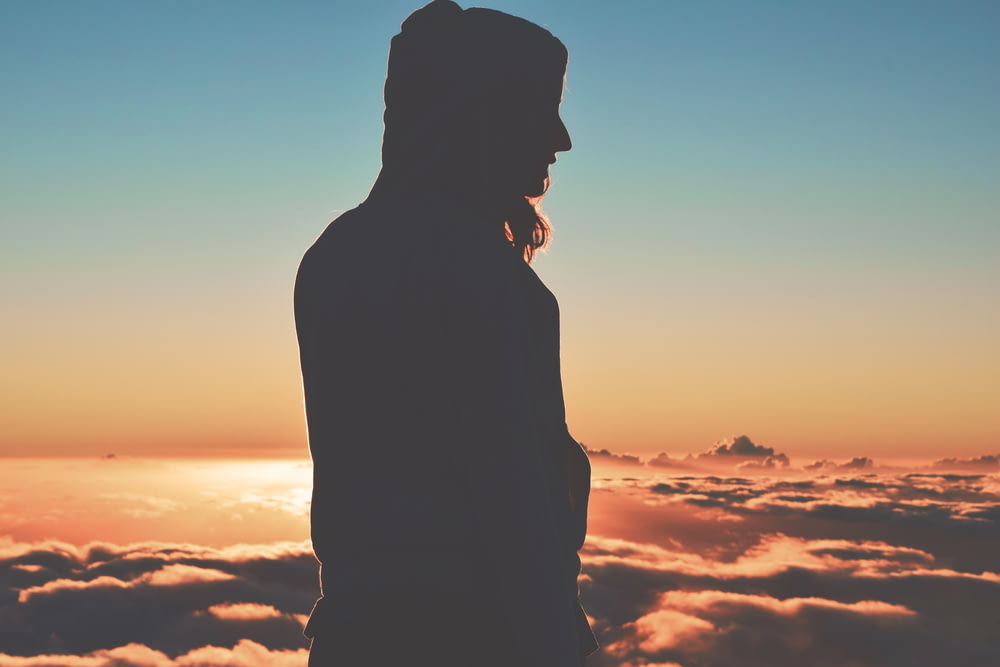 Silhouette einer Person, die Kapuzenpullover auf Wolken trägt