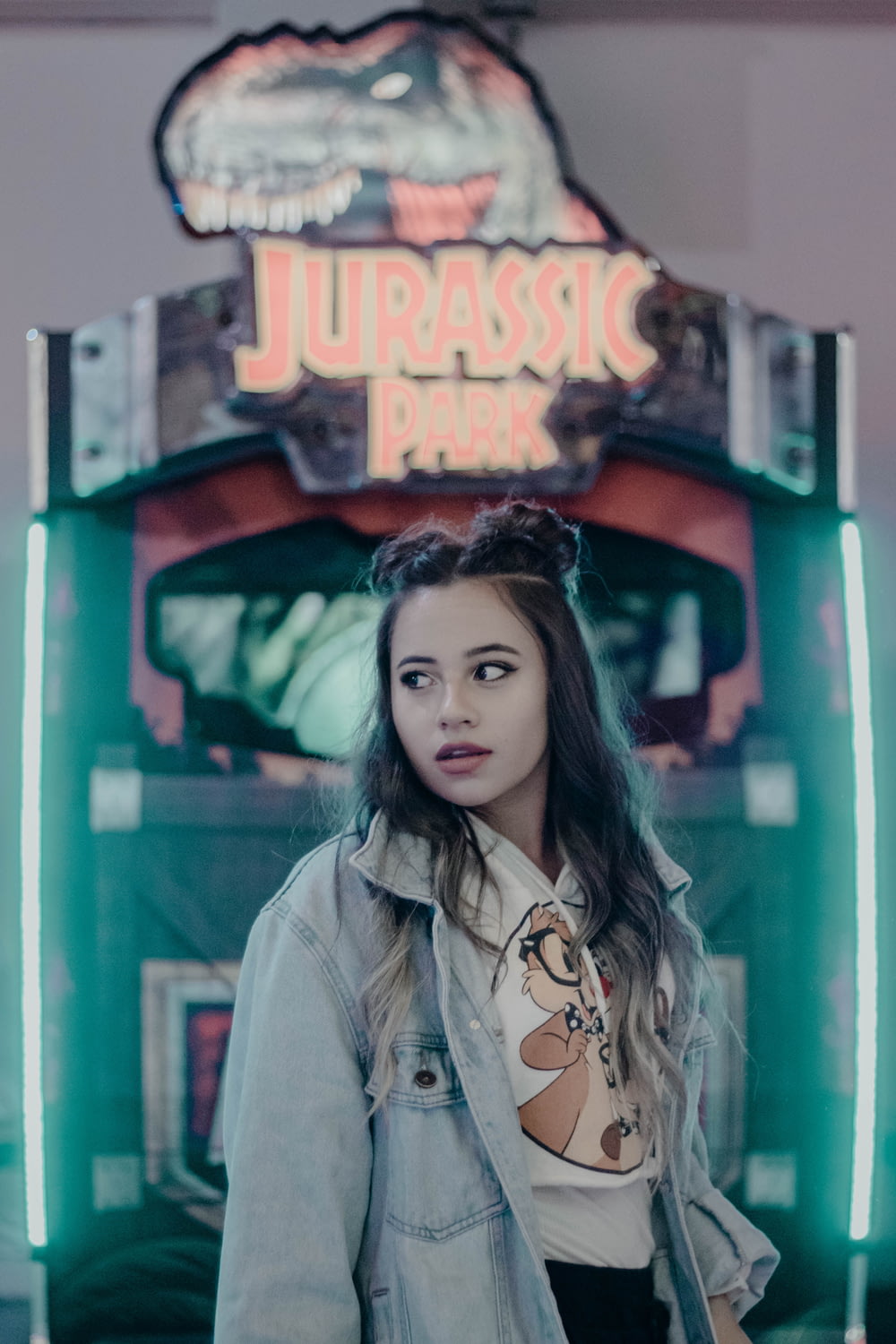 mulher em pé na frente da máquina de jogo arcade Jurassic Park
