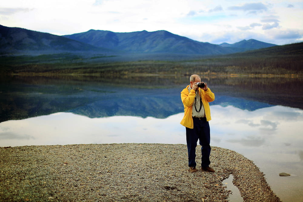 man in yellow jacket taking pictures during daytime