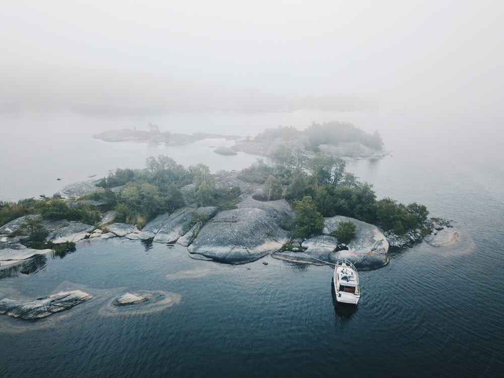 aerial photo of white yacht dock beside gray and green island with mist at daytime