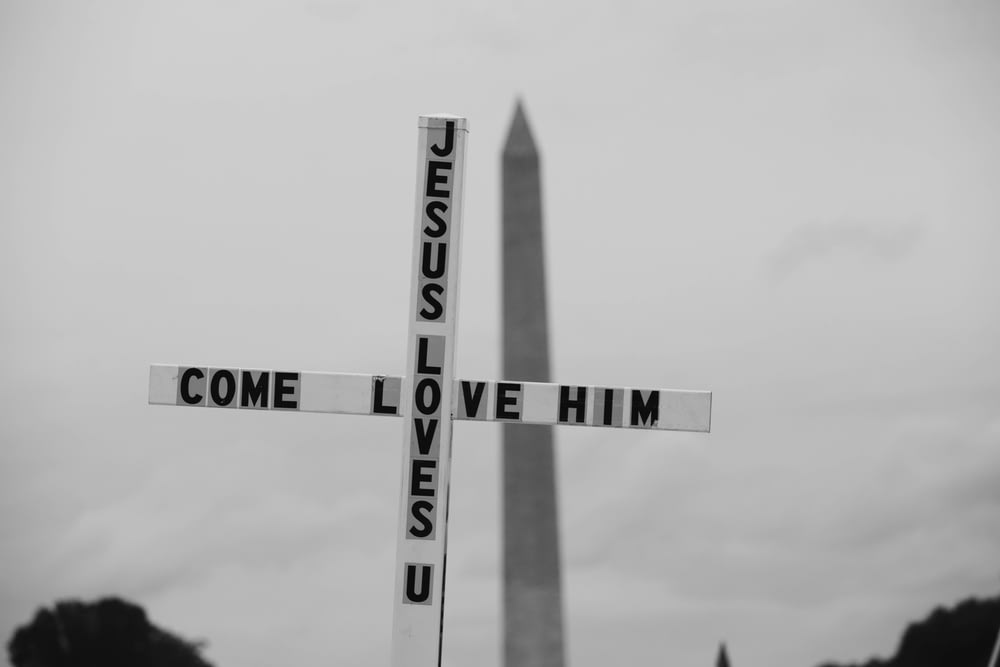a black and white photo of a street sign with the washington monument in the background