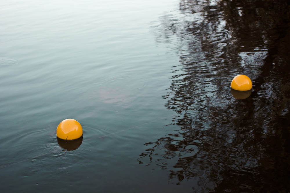 two orange balls on body of water