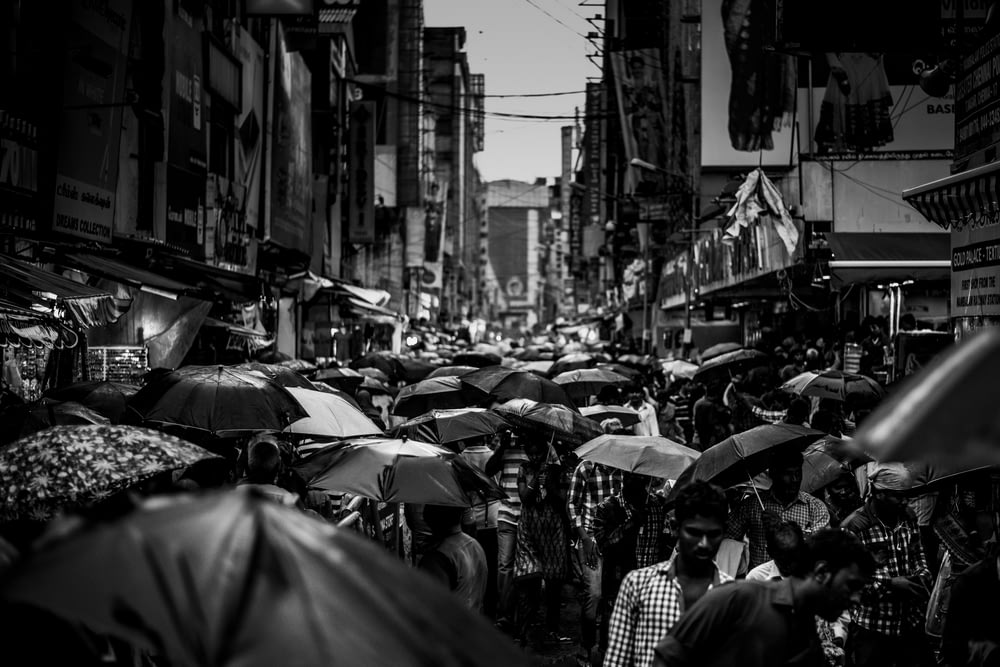 Photographie en niveaux de gris d’un groupe de personnes tenant un parapluie