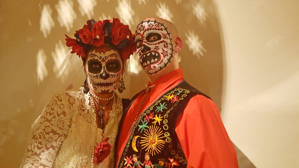 man and woman with face paint standing next to white wall