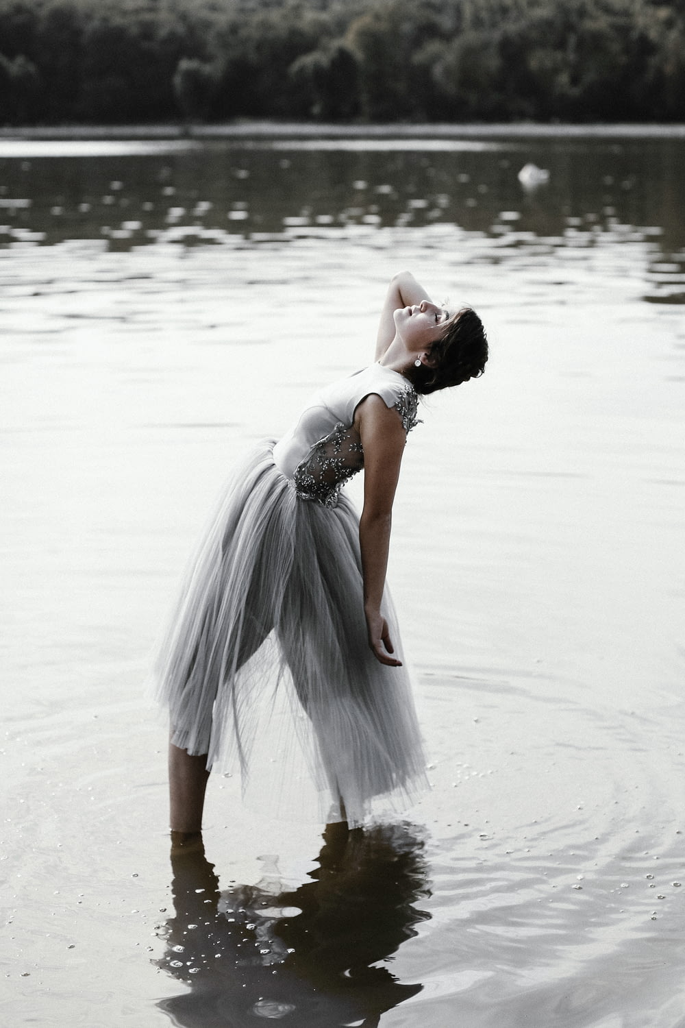 woman in gray dress standing on shallow body of water