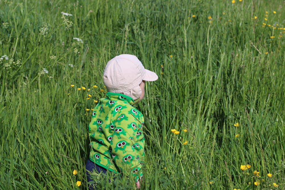 criança caminhando no campo de grama verde durante o dia