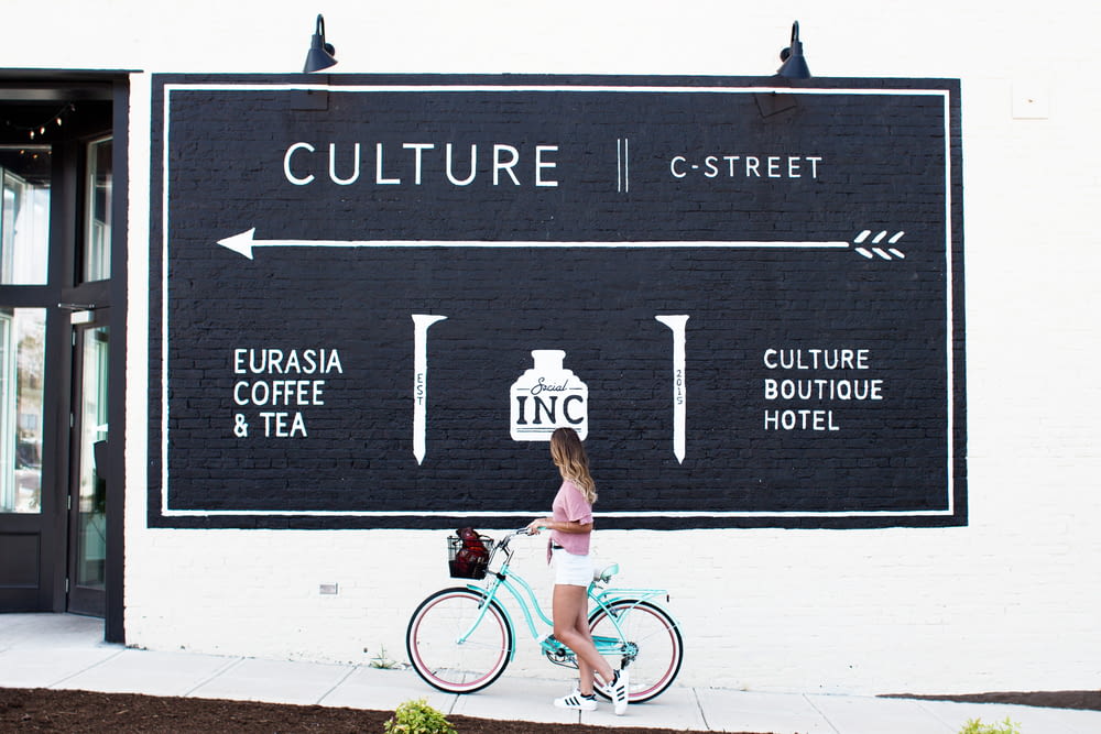 La mujer monta en la bicicleta verde azulado viendo el cartel en la calle