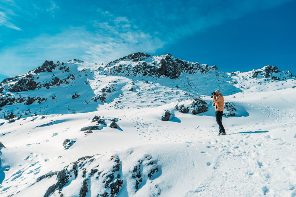 person taking picture on top of snow covered mountain during daytime