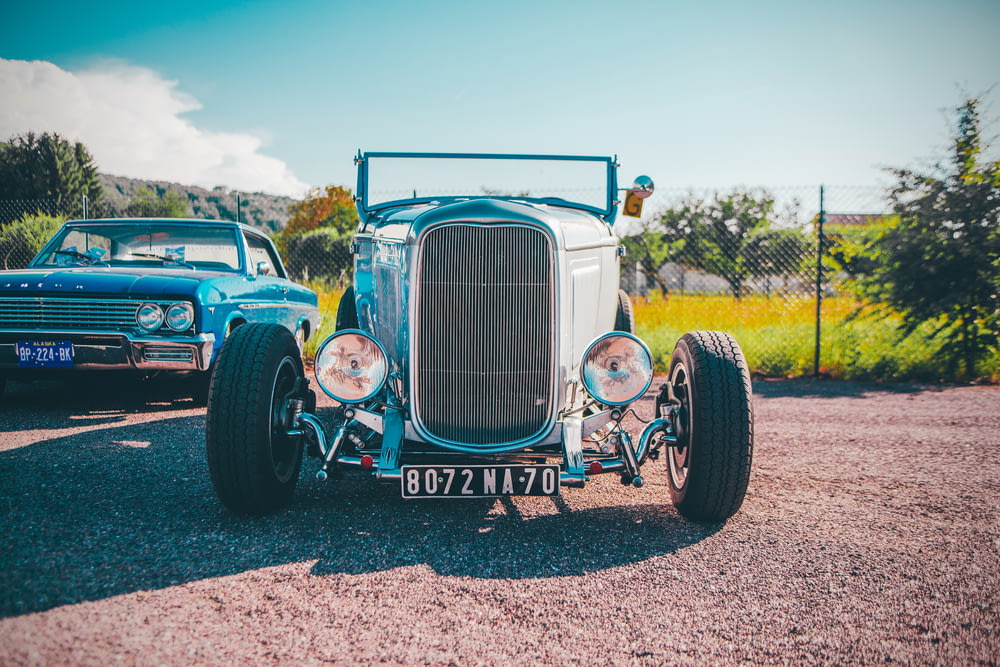a vintage car is parked on a gravel road