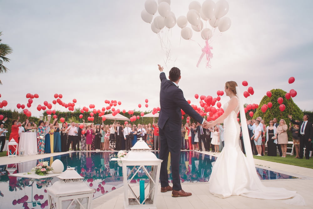 Foto eines Mannes und einer Frau, die frisch heiraten und einen Luftballon halten