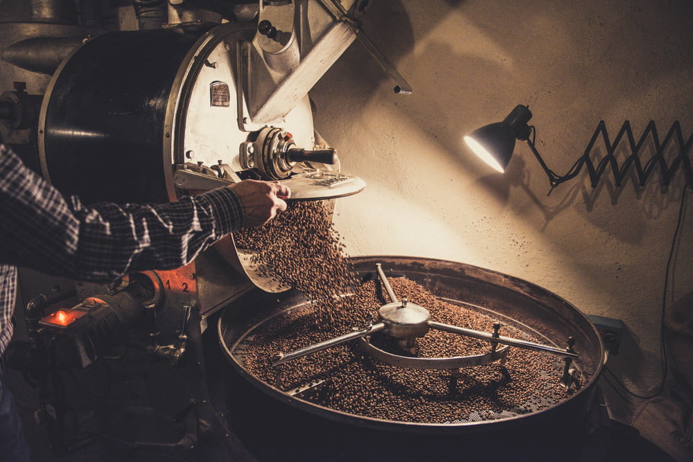 Person, die Kaffeebohnen auf eine Maschine gießt