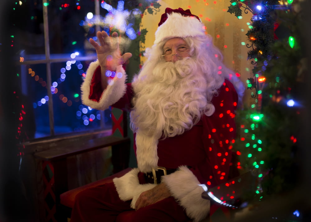 Papá Noel sentado al lado de un árbol iluminado