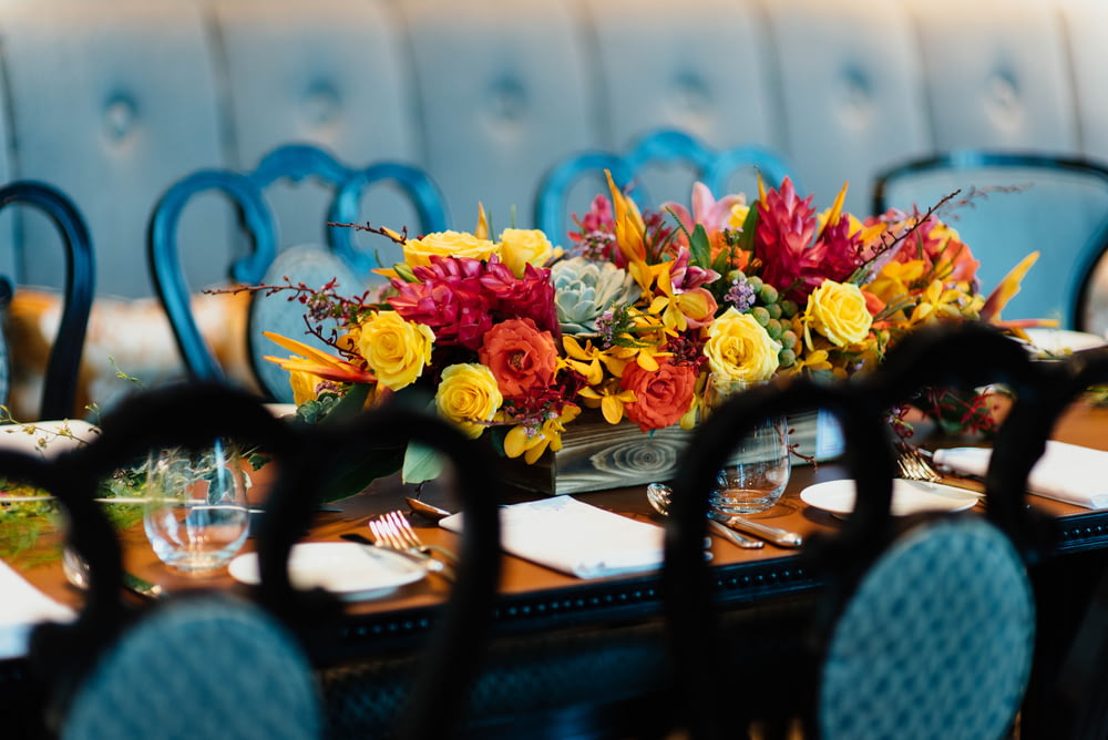 flores vermelhas e amarelas na mesa de jantar de madeira marrom