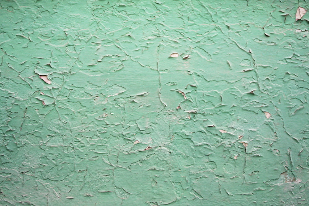 a green wall with peeling paint on it