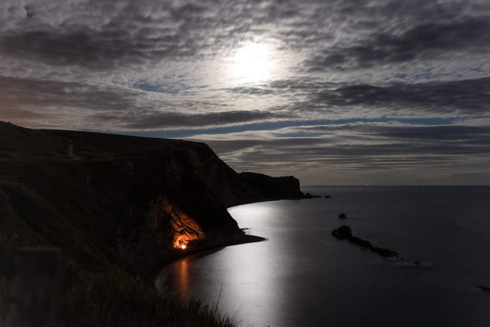 landscape photography of cliff under gray sky at nighttime