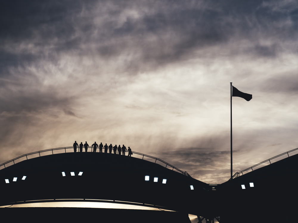 silhouette photo of people standing on bridge
