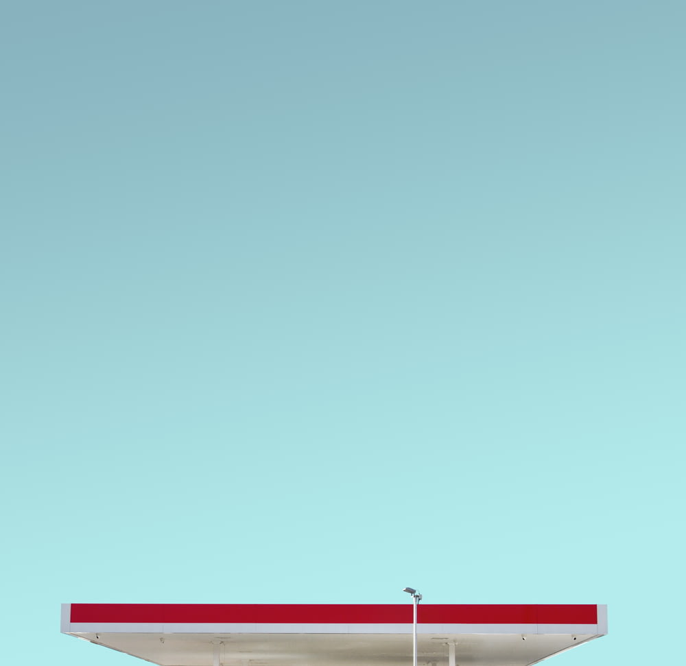 a red and white gas station with a blue sky in the background
